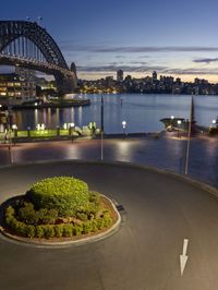 a photo taken at night with a circular clock at the corner and harbour bridge in the background