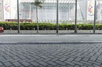 a street in front of a building with an open metal grill in it and people walking along the sidewalk