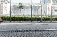 a street in front of a building with an open metal grill in it and people walking along the sidewalk