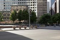 a stone bench on the middle of a city street with tall buildings in the background