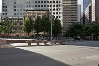 a stone bench on the middle of a city street with tall buildings in the background