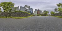 a paved road through an asian city on the other side of tall buildings with trees