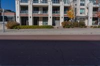 a red fire hydrant in front of an apartment building, with its shadow on the street