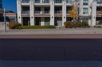 a red fire hydrant in front of an apartment building, with its shadow on the street