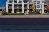 a red fire hydrant in front of an apartment building, with its shadow on the street