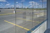 an empty parking lot with a car parked nearby through the glass door of one of the terminal