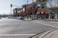 some cars parked at a red light and some people walking by it and buildings with awnings