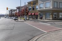 some cars parked at a red light and some people walking by it and buildings with awnings