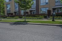 a person on skateboard stands on the street in front of an apartment complex in a city