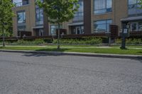 a person on skateboard stands on the street in front of an apartment complex in a city