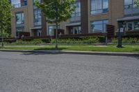 a person on skateboard stands on the street in front of an apartment complex in a city