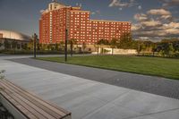 a city street surrounded by grass and tall buildings at the end of a street there is a paved pathway in front of the building