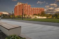 a city street surrounded by grass and tall buildings at the end of a street there is a paved pathway in front of the building