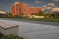 a city street surrounded by grass and tall buildings at the end of a street there is a paved pathway in front of the building