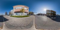 a fisheye lens image of two buildings on a street corner and a person riding a bike