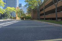 a paved area surrounded by tall buildings and trees with leaves on them, a paved road with a few benches and trees