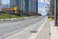 there is an empty street along the street with tall buildings behind it and trees lining the curb