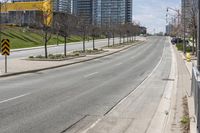 there is an empty street along the street with tall buildings behind it and trees lining the curb