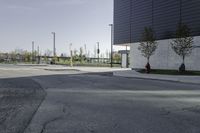 an empty street has a sign in front of it and a building behind it with two trees on each corner