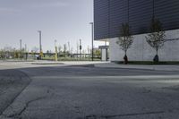 an empty street has a sign in front of it and a building behind it with two trees on each corner