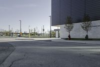 an empty street has a sign in front of it and a building behind it with two trees on each corner