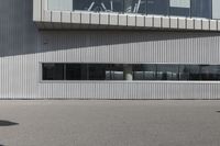 a person standing in front of a building with a skate board in their hands and the shadow on the sidewalk