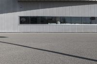 a person standing in front of a building with a skate board in their hands and the shadow on the sidewalk