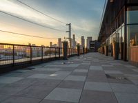 a view of the city skyline from a large walkway at sunset, looking east along the building's facade