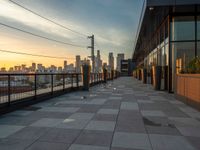 a view of the city skyline from a large walkway at sunset, looking east along the building's facade