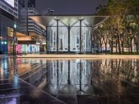 a very nice looking modern building in the city at night time in the rain near some trees