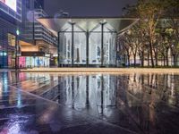 a very nice looking modern building in the city at night time in the rain near some trees