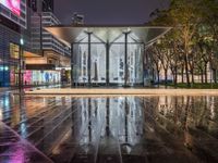 a very nice looking modern building in the city at night time in the rain near some trees