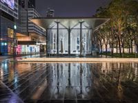 a very nice looking modern building in the city at night time in the rain near some trees