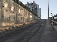 there is a paved sidewalk on the side of this street with the city skyline visible