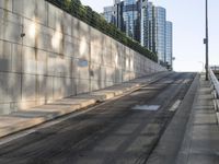 there is a paved sidewalk on the side of this street with the city skyline visible