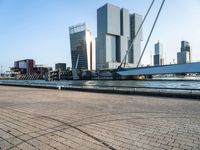 the walkway along the water is a very wide boat dock with some tall buildings and a boat on the other side