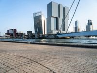 the walkway along the water is a very wide boat dock with some tall buildings and a boat on the other side