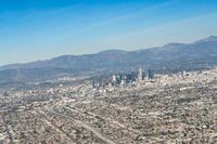 cityscape in front of mountain range from the sky and plane wing view on clear day