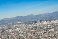 cityscape in front of mountain range from the sky and plane wing view on clear day