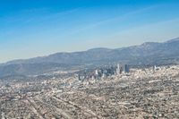 cityscape in front of mountain range from the sky and plane wing view on clear day