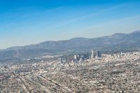 cityscape in front of mountain range from the sky and plane wing view on clear day