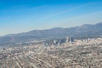 cityscape in front of mountain range from the sky and plane wing view on clear day