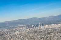 cityscape in front of mountain range from the sky and plane wing view on clear day