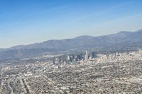 cityscape in front of mountain range from the sky and plane wing view on clear day