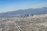 cityscape in front of mountain range from the sky and plane wing view on clear day