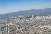 cityscape in front of mountain range from the sky and plane wing view on clear day