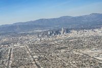 cityscape in front of mountain range from the sky and plane wing view on clear day