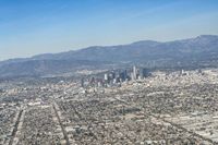 cityscape in front of mountain range from the sky and plane wing view on clear day