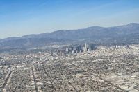 cityscape in front of mountain range from the sky and plane wing view on clear day