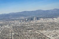 cityscape in front of mountain range from the sky and plane wing view on clear day